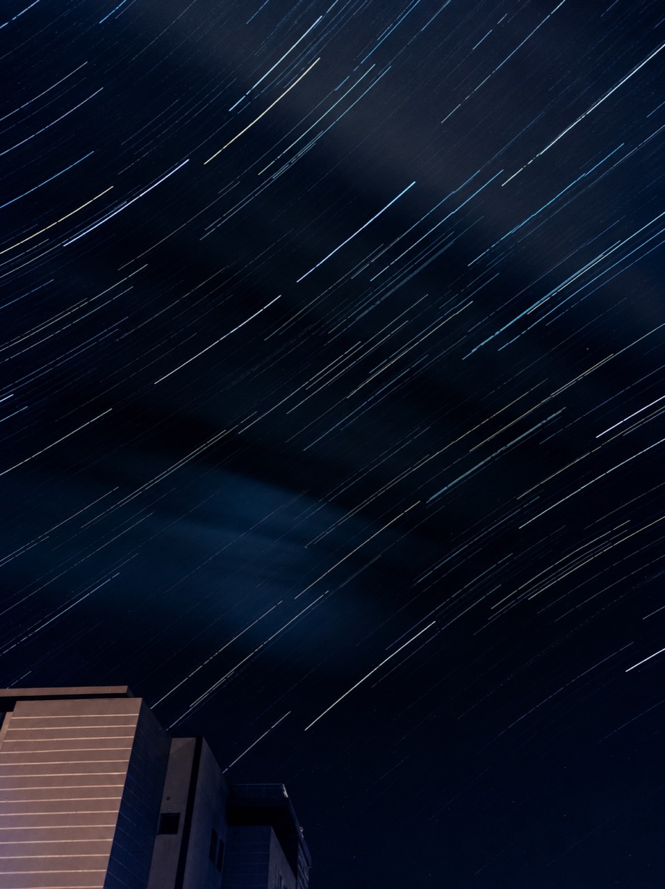 Long-exposure star trails over a building edge